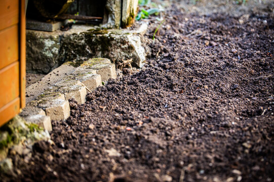 Freshly dug soil in the garden, behind it a garden shed