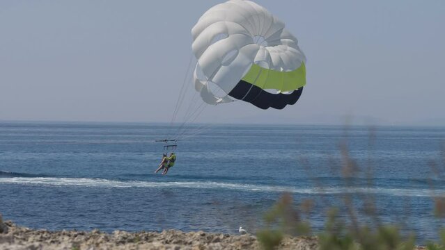 Tourists couple enjoy water sports by parasailing on sea