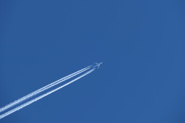 Four-engined jet aircraft in the blue sky and its contrail