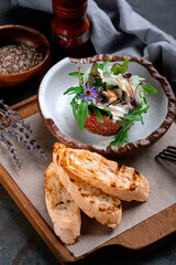 Beef tartare with chopped meat and decorated with arugula leaves and parmesan. Round-shaped raw beef dish