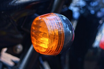 one small round red glass headlight turn signal on a black motorcycle on the street