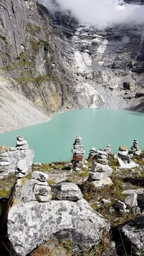 4K vertical video shot of Sabai Tso glacial lake at cca 4350m stones Stacked in Cairns Glacier falling in high altitude natural reservoir. Makalu Barun National Park, Mera peak climbing route, Nepal.