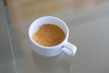 Hot coffee in white cup on Glass table. Top view of coffee in cup with background focus.