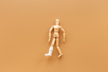 Wooden dummy man with leg broken - leg in bandage. Medical insurance and healthcare concept