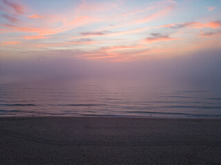 Fototapeta premium Aerial view of a sunrise sea with a blanket of morning fog and morning sunbeams shining through