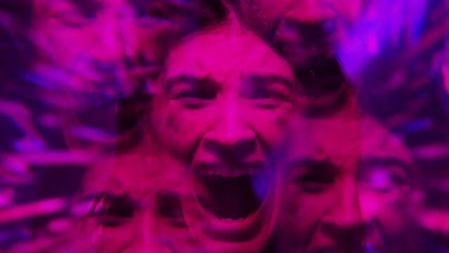 Kaleidoscope effect video of young terrified woman screaming at camera in purple neon light