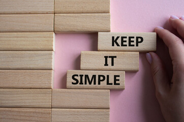 Keep it Simple symbol. Concept words Keep it Simple on wooden blocks. Businessman hand. Beautiful pink background. Business and Keep it Simple concept. Copy space.