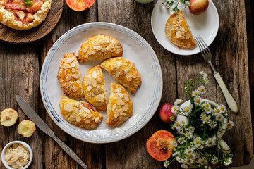 Mini cottage cheese pies with nectarines and peach decorated with almond petals. Empanadas. Shortbread dough.
