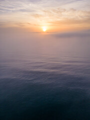 Obraz premium Aerial view of a sunrise sea with a blanket of morning fog and morning sunbeams shining through