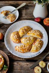 Mini cottage cheese pies with nectarines and peach decorated with almond petals. Empanadas. Shortbread dough.