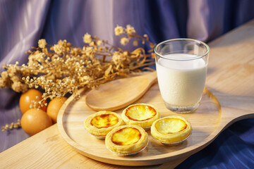 Egg tart with a glass of milk on a wooden table
