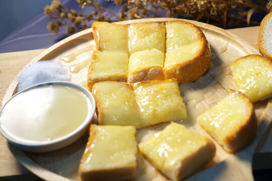 Toast bread with butter and honey on wooden plate