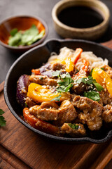 Asian pork with vegetables and glass noodles in a pan on the black background vertical photo
