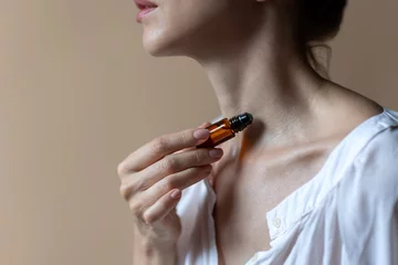 Woman applying natural rollerball aroma oil on her neck  close up  © orlio