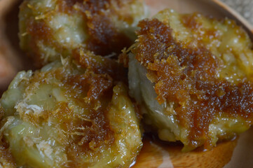 Kue Lupis is a traditional Indonesian sweet sticky cake made from glutinous rice with grated coconut and palm sugar syrup. Selective focus.