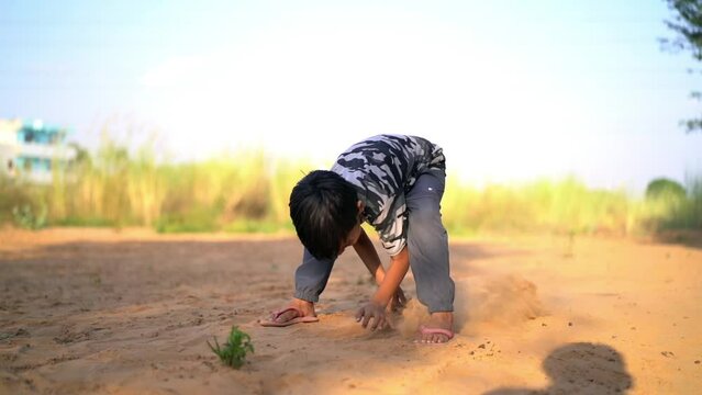 The Dirty hands of a little boy child are digging in the dry mud. Smiling little asian boy have fun digging sand.