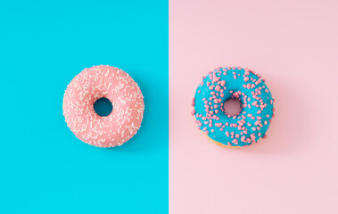 Pink and blue glazed donuts on light blue and pastel pink background. Creative concept. Minimal delicious food idea. Flat lay yummy donut composition. Donuts aesthetic.