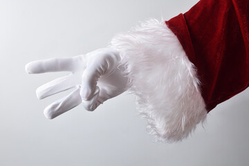 Santa Claus hand showing three fingers wearing gloves dressed traditionally