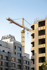 Fototapeta na wymiar Construction crane and high-rise buildings under construction. Facades of multi-storey buildings under construction