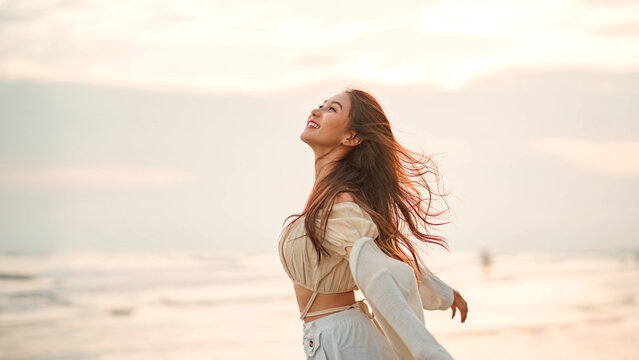 Side view of young asian woman with freedom on the sea beach at golden sunset, Female tourist on seaside summer vacation, Go Everywhere. - Powered by Adobe