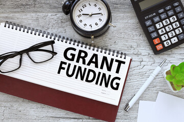 Grant funding symbol. text on the page on the diary. a table clock. glasses. Business and grant funding concept. Copy space.