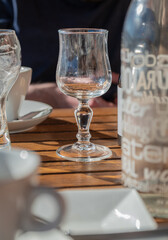 empty wine glass on wooden restaurant table in sunlight