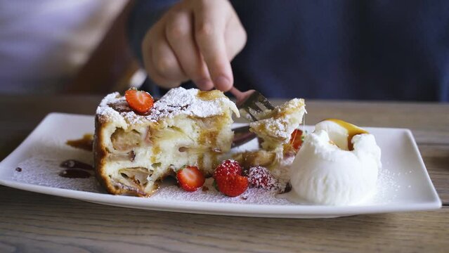 A teenager eats dessert, apple strudel and ice cream decorated with strawberries. Dessert dishes, breakfast. Close-up