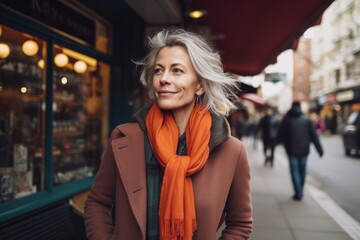 Portrait of smiling mature woman in coat and scarf walking on city street