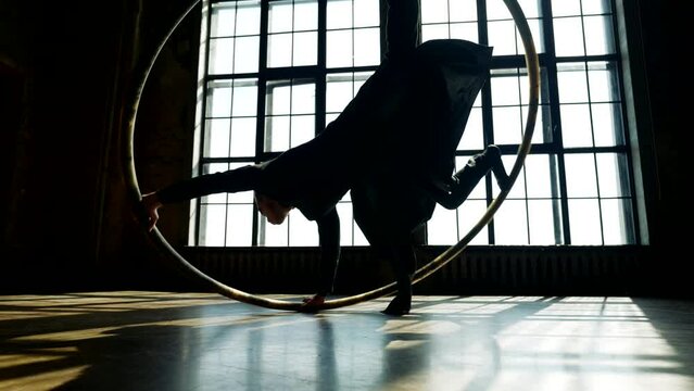male dancer in image of movie character dancing acrobatic dance with hoop, slow motion