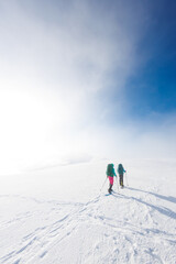 Fototapeta na wymiar climbers climb the mountain in the snow. Winter mountaineering. two girls in snowshoes walk through the snow. mountaineering equipment. hiking in the mountains in winter.