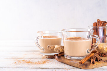 Cinnamon Stick sore throat tea with milk, with ginger and coconut non-dairy milk, on white wooden kitchen table, copy space