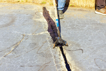 Worker patcher performs coating, crack sealing, bitumen emulsion road surface restoration during...