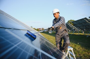Indian handyman cleaning solar panels form dust and dirt