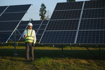 Industrial senior man engineer walking through solar panel field for examination