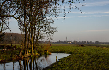 The countryside of Groningen, the Netherlands. The beautiful blue and white tower of the Mariakerk in Uithuizermeeden on the horizon.