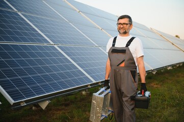 Portrait of senior worker in uniform standing near solar panels