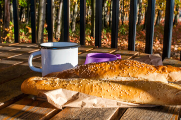 Cozy autumn still life. Two cups of coffee and baguettes on a wooden table on a background of fallen golden leaves