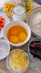 baking ingredients: eggs in a bowl, sugar, flour, corn, milk in a glass, pepper