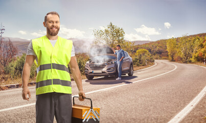 Man with a car breakdown on the road and a road help worker holding a tool box