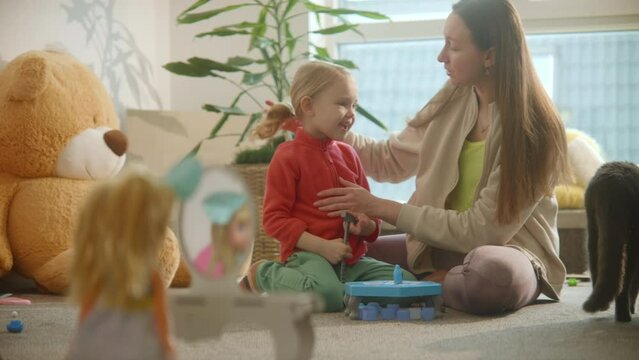 Mother and daughter talking and playing busily at nursery room background, nice casual interior. Doll stands at the toy table mirror. Family playtime delight, family bonds. High Quality 4k footage