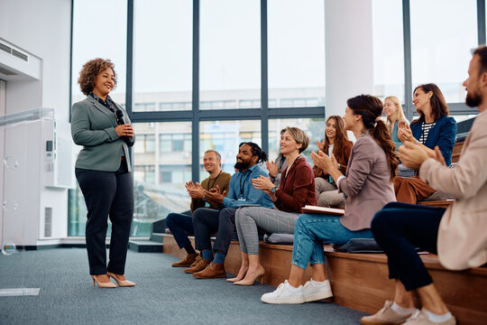 Mature businesswoman getting applause after successful speech during seminar in conference hall.