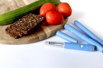 Insulin injection pen and cutting board with tomato, bread and cucumber,