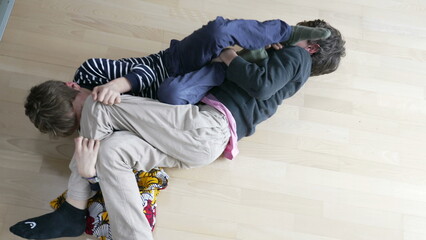 Brotherly Battle, Siblings Engaging in Floor Wrestling and Quarreling. Sibling Rivalry, Brothers Wrestling on Floor in Spirited Quarrel