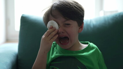Crying small boy with hurt eye emergency, open mouth tearful child feeling pain after accident,...