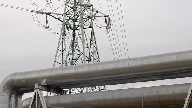 pipeline and power transmission tower close-up against a background of gray sky
