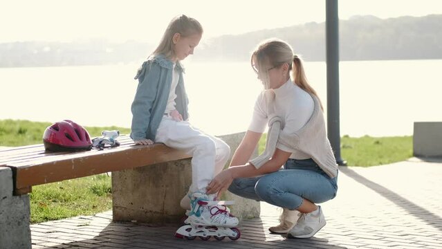 Mon helping her daughter in the park rollerblading enjoying there time togeather