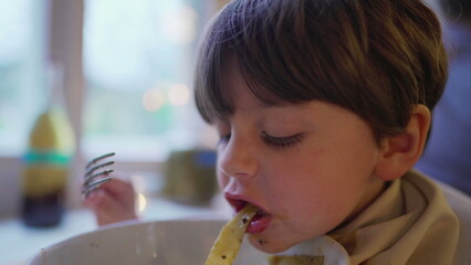 Close-up child enjoying spaghetti pasta on bowl, little boy eating Italian food at restaurant with napkin on collar - obrazy, fototapety, plakaty