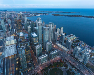 The view of downtown Toronto skyline skyscrapers from the top of CN tower. Lake at dawn, city light bright night long exposure aerial above view