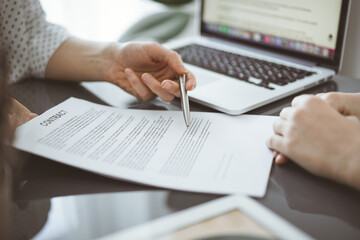 Business people sitting and discussing contract in office, closeup. Partners or lawyers working together at meeting before signing papers. Teamwork and partnership