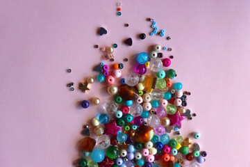 Various colorful beads on bright pink background. Top view.